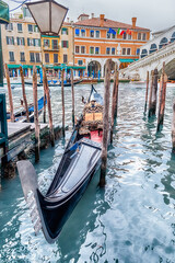 Fototapeta na wymiar Traditional gondola docked next to Rialto Bridge in Venice, Italy