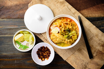 Northern Thai food (Khao Soi), Spicy curry noodles soup with chicken eating with crispy deep-fried egg noodles, pickled mustard, shallots, lime and ground chillies fried in oil