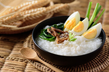 Asian food, Rice soup with boiled egg, grilled mushroom and spinach in a bowl on woven rattan sheet