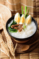 Asian food, Rice soup with boiled egg, grilled mushroom and spinach in a bowl on woven rattan sheet