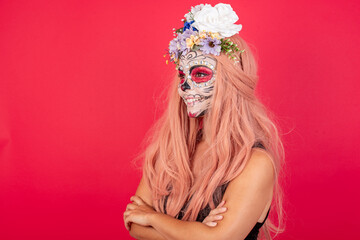 Cheerful lovely young beautiful woman wearing halloween make up over red background crossing arms looking aside having a nice conversation