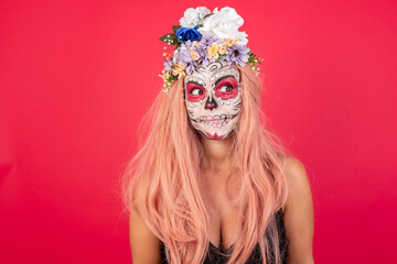 Photo of amazed young beautiful woman wearing halloween make up over red background bitting lip and looking up to empty space,
