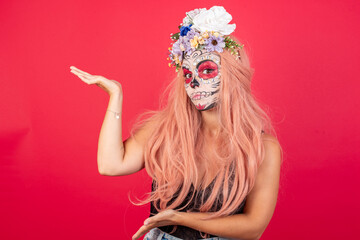 young beautiful woman wearing halloween make up over red background pointing aside with both hands showing something strange and saying: I don't know what is this. Advertisement concept.