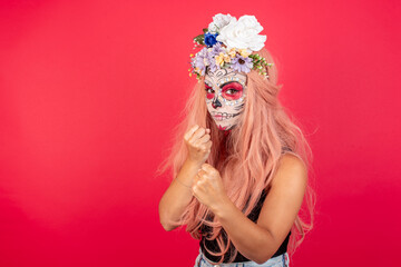 young beautiful woman wearing halloween make up over red background Ready to fight with fist defense gesture, angry and upset face, afraid of problem.