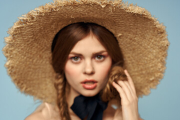 Girl in a straw hat portrait close-up pigtails fun red hair blue background