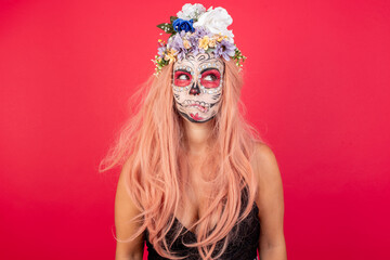 Portrait of Young beautiful woman wearing halloween make up over red background making grimace and...