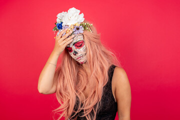 A very upset and lonely young beautiful woman wearing halloween make up over red background crying,