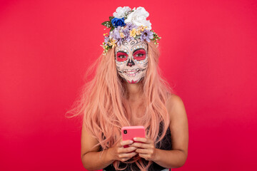 young beautiful woman wearing halloween make up over ed studio enjoys distant communication, uses mobile phone, surfs fast unlimited internet, has pleasant smile.