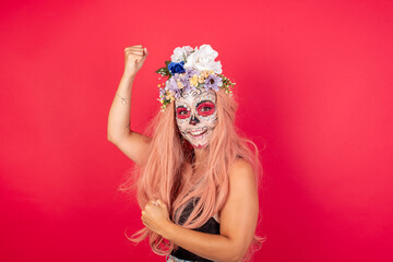 Young beautiful woman wearing halloween make up over red background raising fists celebrating black friday shopping