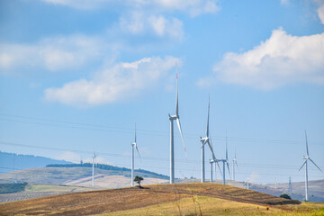 Fototapeta na wymiar Barren hilly landscape with several wind turbines under a blue sky.