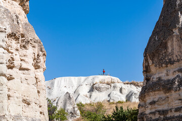 Woman alone with the volcanic landscape in Cappadocia. Girl walking around Fairy chimneys, Turkey.