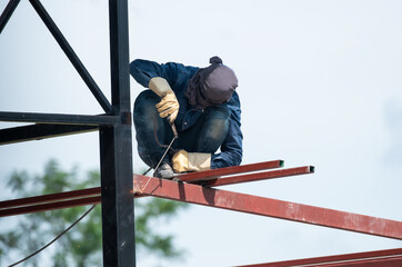 a man works with a welding machine and metal on the roof