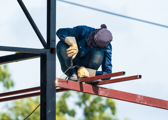 a man works with a welding machine and metal on the roof