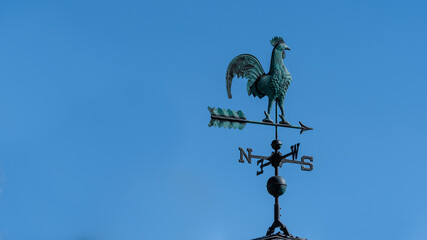 Weather vane on a rooftop with copy space blue background. Rooster wind vane and polar compass...