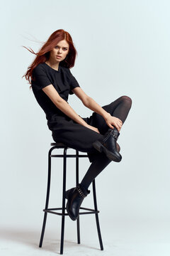 woman high chair indoors full length black dress red hair model boots