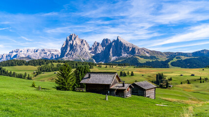 Wooden chalets in Dolomites, Odle Mountains in the background of the Seceda Mountains, Trentino...