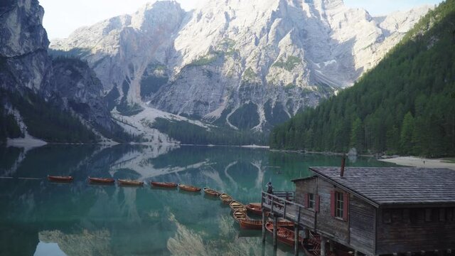Photographer taking pictures of a magical lake during sunrise at Lago di Braies in the Dolomites.