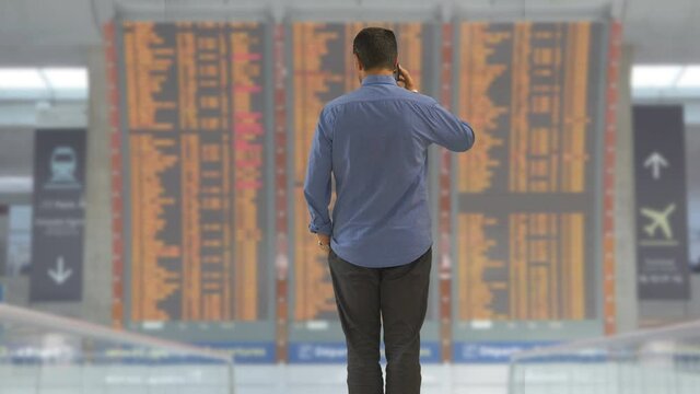 Man at airport timetable watch clock worried lost or cancelled flight departure