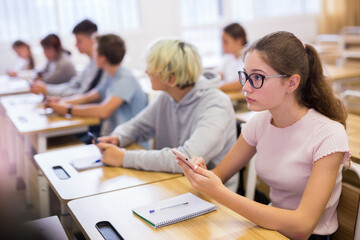 Portrait of teen pupils using mobile phones during lesson