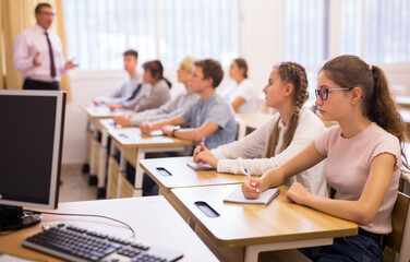 Group of focused teenage students sitting at classroom working at class