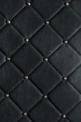 Close up. Dark black leather texture background with shiny pin.