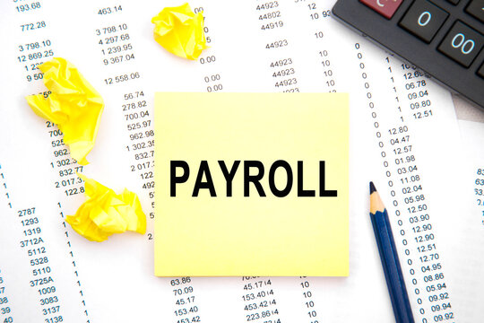 TEXST PAYROL on white card with blue metal pen and paper clips on financial table. Business and financial concept