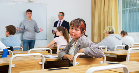 Portrait of asian teenage schoolgirl sitting on lesson in classroom, looking at camera..