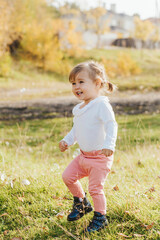 Happy little girl of European appearance is running. Beautiful yellow autumn in the park. Bright sunlight.
