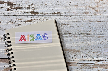 There is a card on the table with "AISAS" (Attention, Interest, Search, Action, Share) written on it, on a notebook.