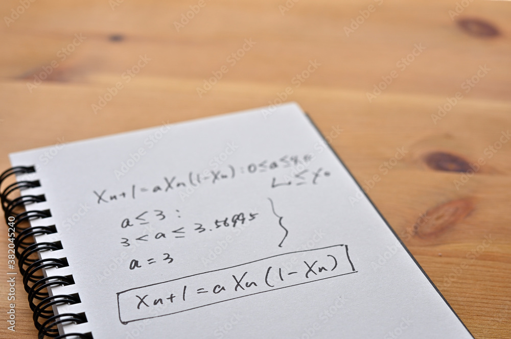 Poster a notebook with chaos theory formulas on it sits by the window.