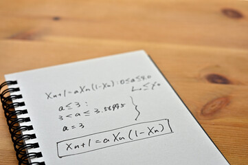 A notebook with chaos theory formulas on it sits by the window.