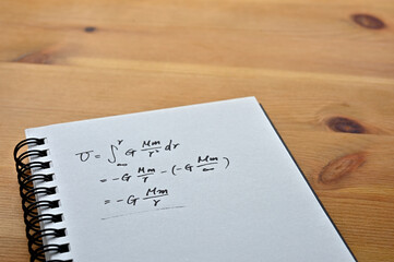 Close up of the notes with the formula for the law of universal gravitation.