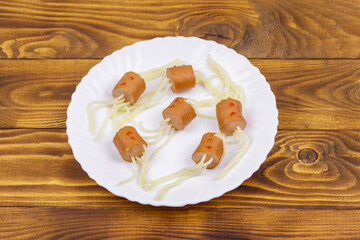 Spaghetti with sausages in the shape of spiders for Halloween party on wooden table