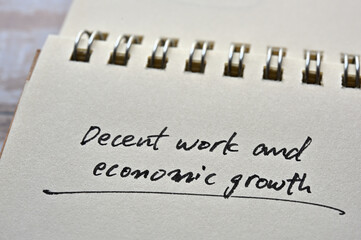 At the edge of the notebook, "Decent work and economic growth" is written. Close-up.