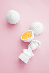 citrus orange painted white with small bust on pale pink background 