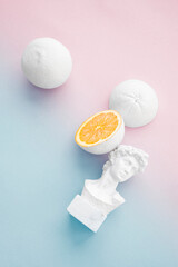 citrus orange painted white with small bust on pale pink and baby blue background 