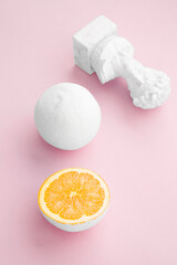 citrus orange painted white with small bust on pale pink background 