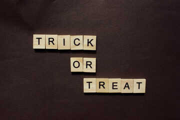 Word Trick or Treat. Wooden blocks with an inscription on a black background. The bulletin board. The concept is the Holiday Halluin. View from above. Copy space for text