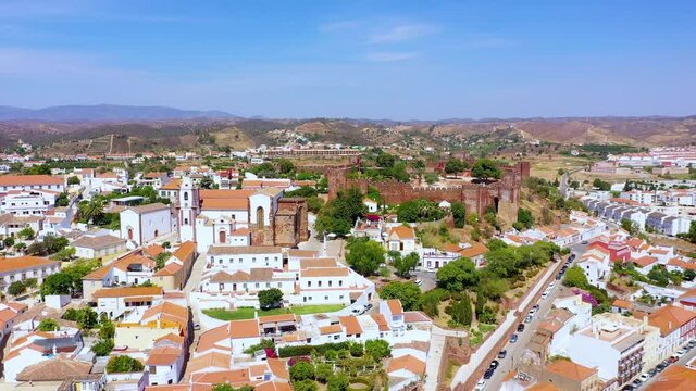 Aerial view away from the Cathedral and the castle of Silves, sunny day, in Faro, Algarve, Portugal - pull back, drone shot