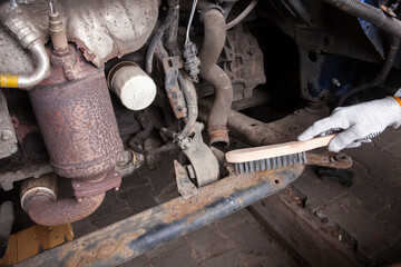 A car mechanic cleans and maintains the engine chassis of an old car against corrosion and protects it with a preparation