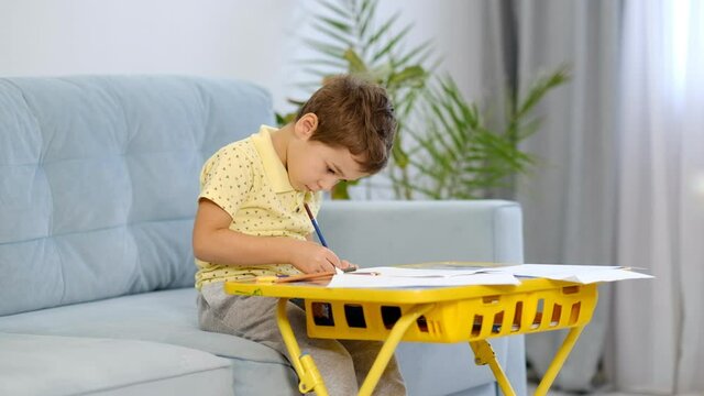 little cute boy draws with pencils. the child is engaged in creativity at home