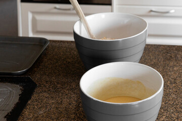 Mixing bowls on kitchen bench with wooden spoon & oven trays.