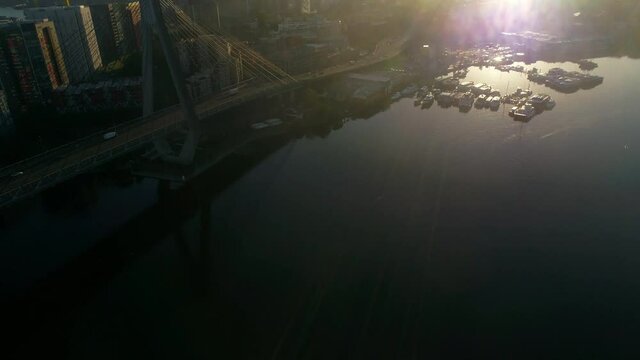 Aerial view of ANZAC Bridge and Sydney skyline during sunset, tilt reveal
