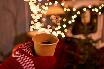 Christmas Market in European small city. Hand holding a cup of mulled wine with blurred background of winter wonderland, a