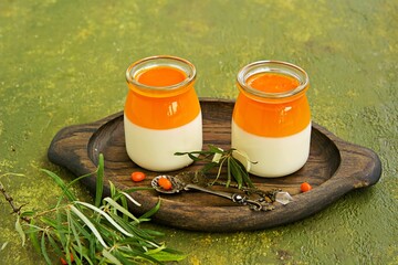 Dessert, creamy panna cotta with sea buckthorn jelly in vintage glass jars on a wooden board or...