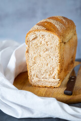 Sliced loaf of bread on cutting board with knife and cloth