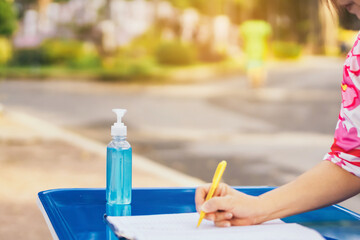 Blue alcohol gel bottle and a register book on the table for athletes to prevent Corona Virus (COVID -19) infection and spread before exercising in public park. New normal lifestyle. Selective focus