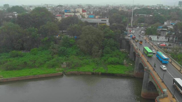 falling drone shot looking down traffic on Chhatrapati shivaji road shanniwar wada fort mula mutha river old pune city heritage site India