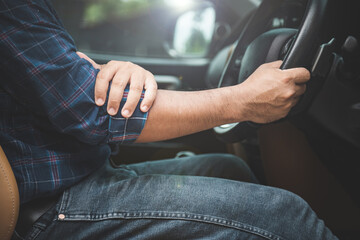 Injury or tired from long driving concept : Man use hands to hold and massage on his elbow in the car while stop.
