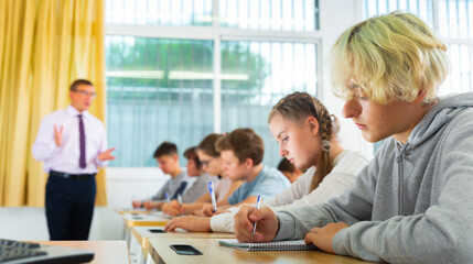 Fototapeta premium Teen students listening lecture of teacher, smart young people studying at college